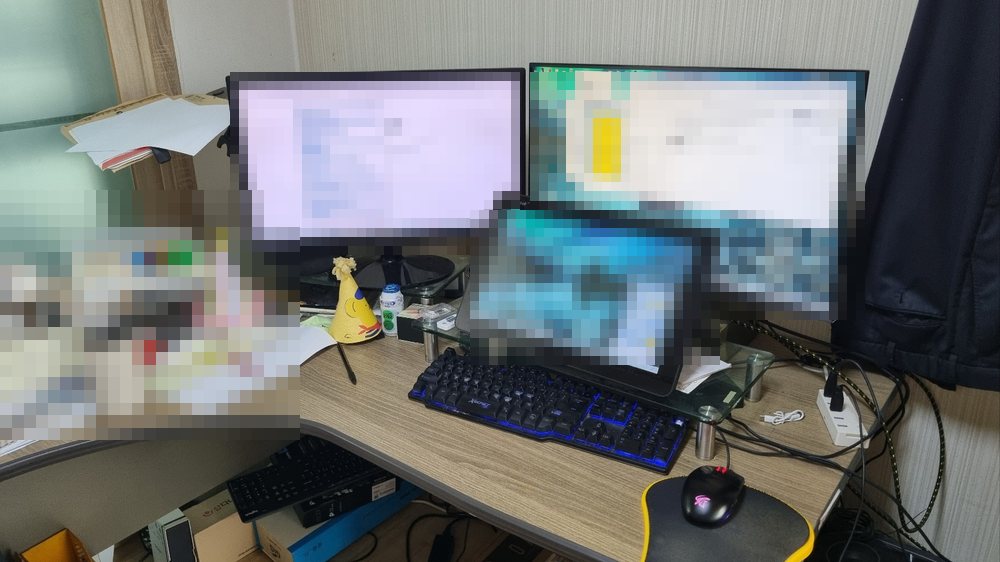 인간 직원이 일하는 책상. 모니터와 서류는 모자이크 처리됨